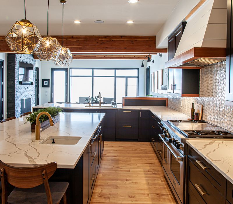 This mid-century modern home includes dramatic central stringer stairs behind a glass wall, white chevron tiles with dark grout, retro furniture, brushed gold fixtures, black cabinets, and laminated beams. 