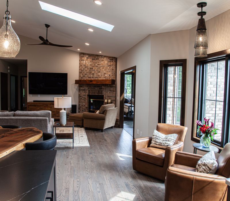 This house includes a brushed steel range hood, a live edge countertop, stone-seeded glass pendant lamps, skylights, and a barn door pantry. 