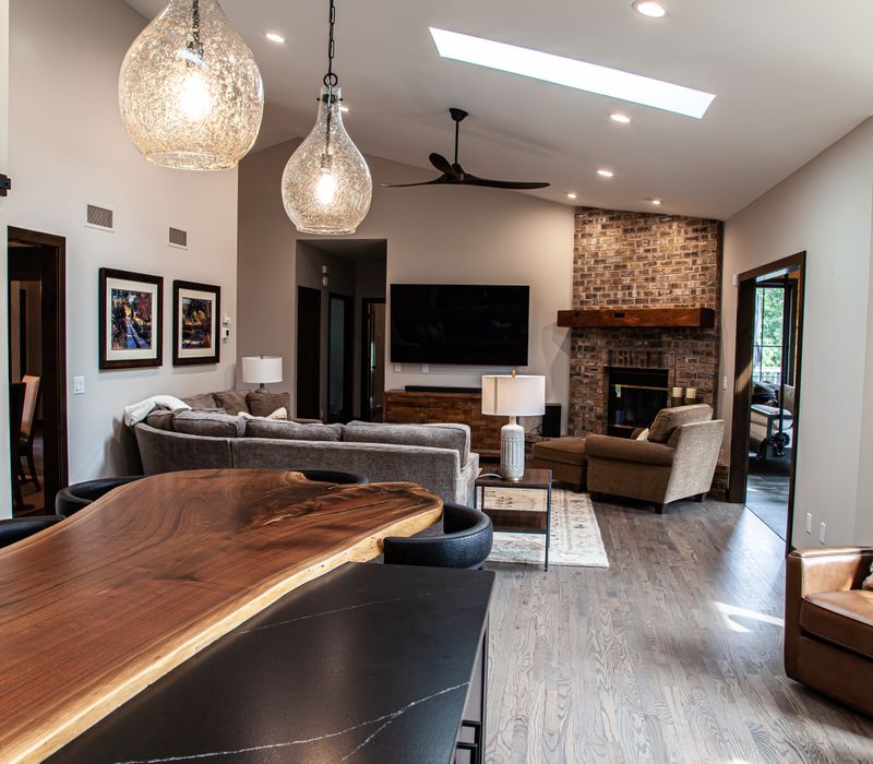 This house includes a brushed steel range hood, a live edge countertop, stone-seeded glass pendant lamps, skylights, and a barn door pantry. 