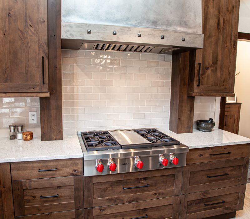 This house includes a brushed steel range hood, a live edge countertop, stone-seeded glass pendant lamps, skylights, and a barn door pantry. 