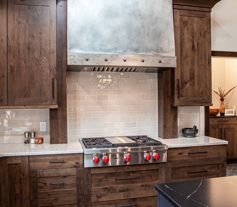 This house includes a brushed steel range hood, a live edge countertop, stone-seeded glass pendant lamps, skylights, and a barn door pantry. 