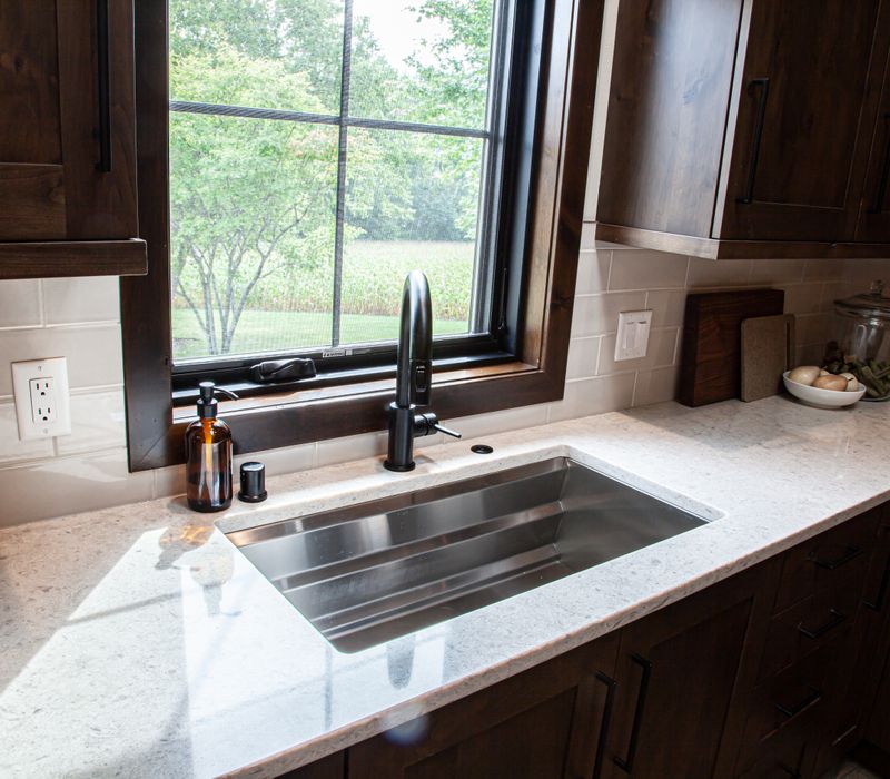 This house includes a brushed steel range hood, a live edge countertop, stone-seeded glass pendant lamps, skylights, and a barn door pantry. 