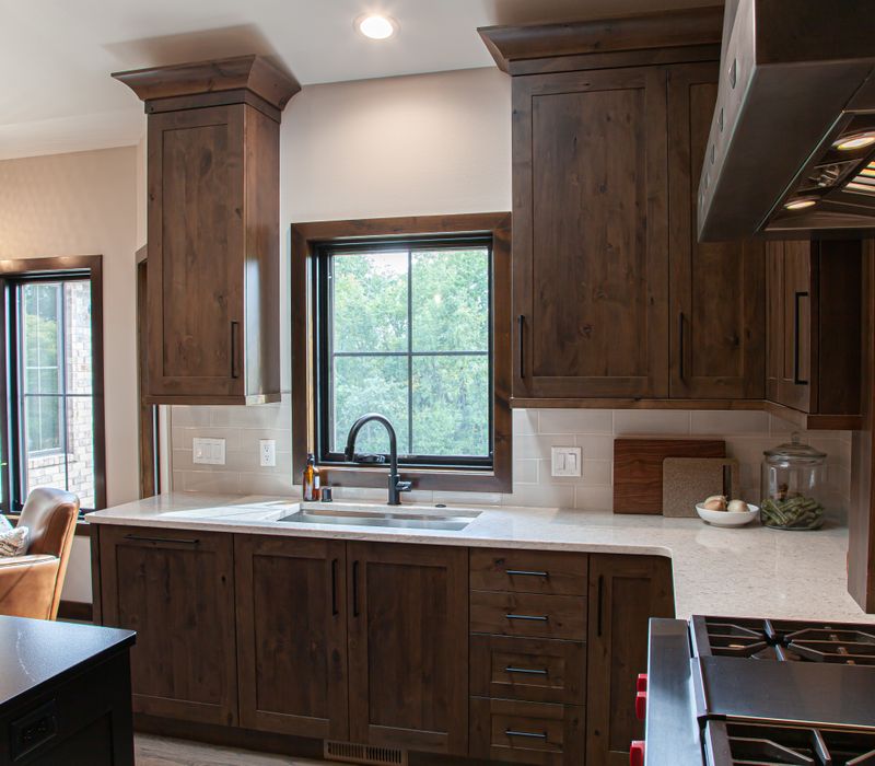 This house includes a brushed steel range hood, a live edge countertop, stone-seeded glass pendant lamps, skylights, and a barn door pantry. 