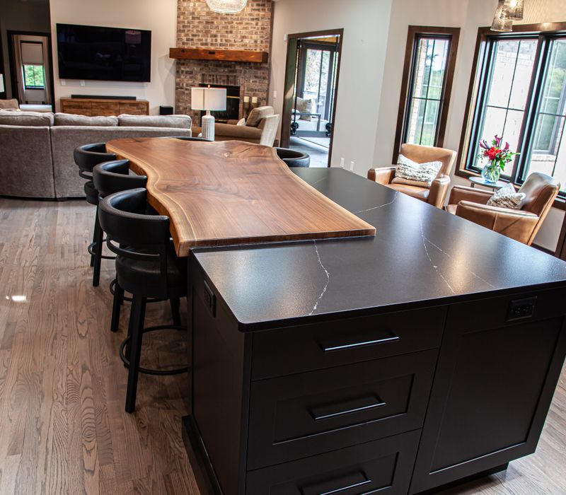 This house includes a brushed steel range hood, a live edge countertop, stone-seeded glass pendant lamps, skylights, and a barn door pantry. 