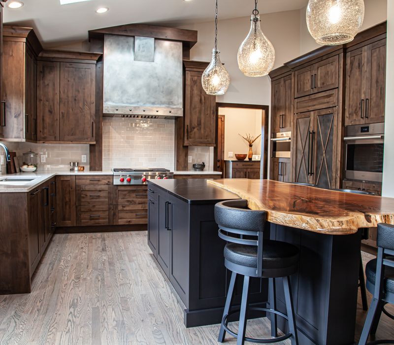 This house includes a brushed steel range hood, a live edge countertop, stone-seeded glass pendant lamps, skylights, and a barn door pantry. 