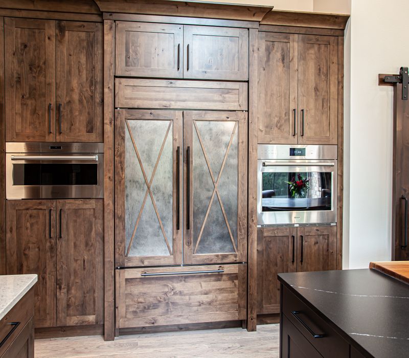 This house includes a brushed steel range hood, a live edge countertop, stone-seeded glass pendant lamps, skylights, and a barn door pantry. 
