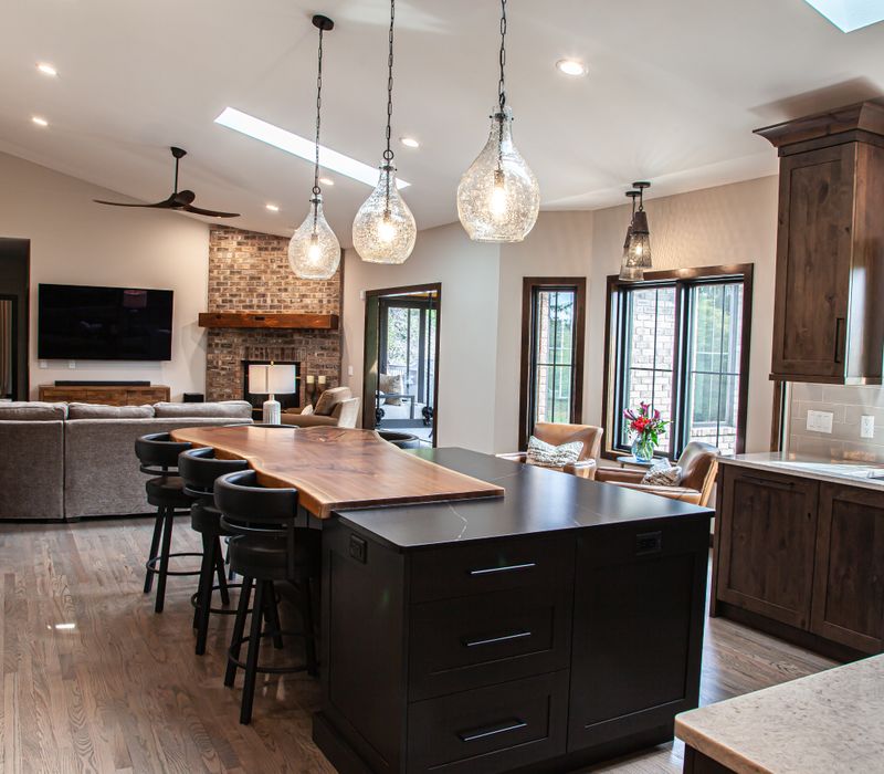 This house includes a brushed steel range hood, a live edge countertop, stone-seeded glass pendant lamps, skylights, and a barn door pantry. 