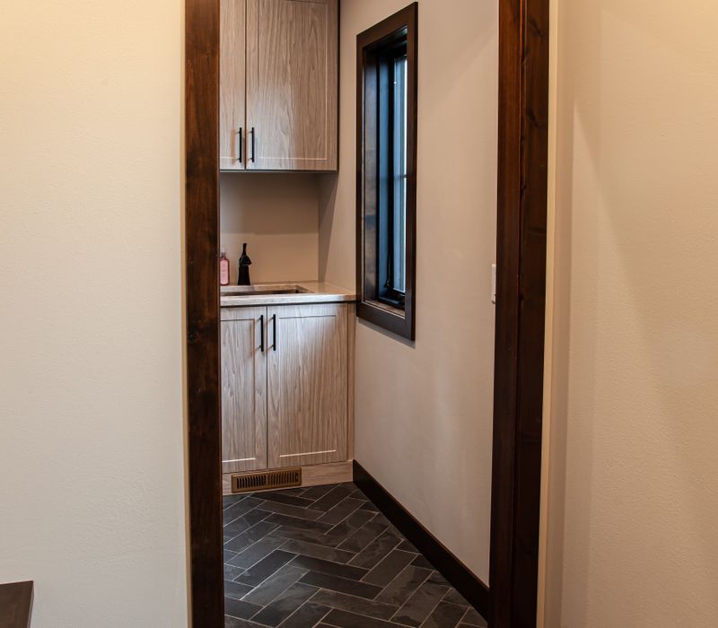 This house includes a brushed steel range hood, a live edge countertop, stone-seeded glass pendant lamps, skylights, and a barn door pantry. 