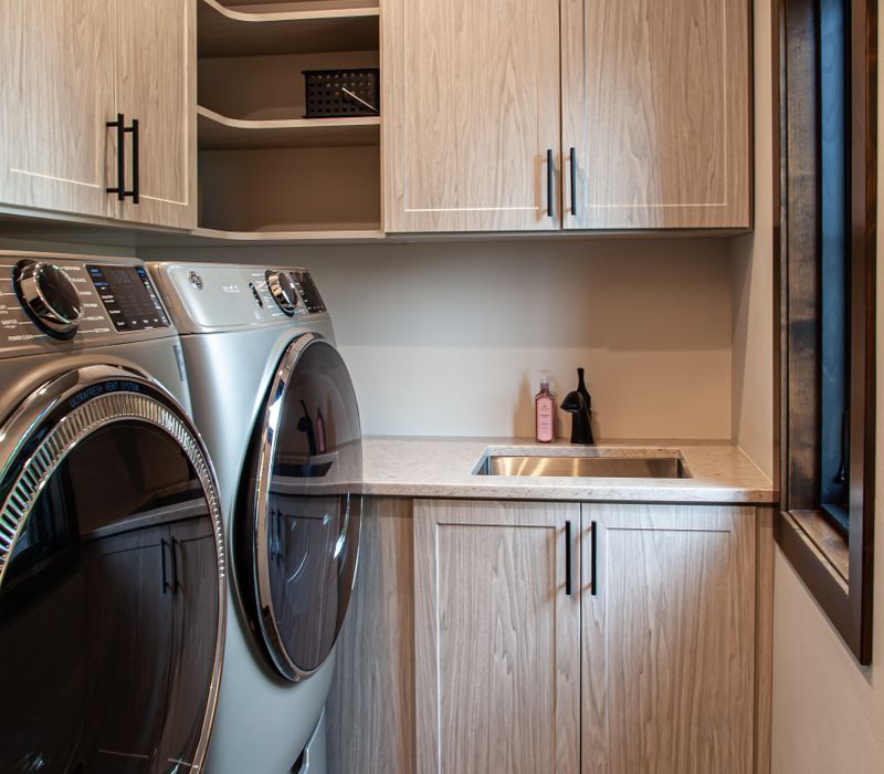 This house includes a brushed steel range hood, a live edge countertop, stone-seeded glass pendant lamps, skylights, and a barn door pantry. 