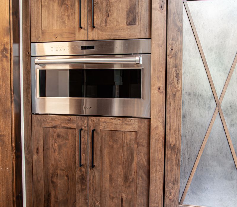 This house includes a brushed steel range hood, a live edge countertop, stone-seeded glass pendant lamps, skylights, and a barn door pantry. 