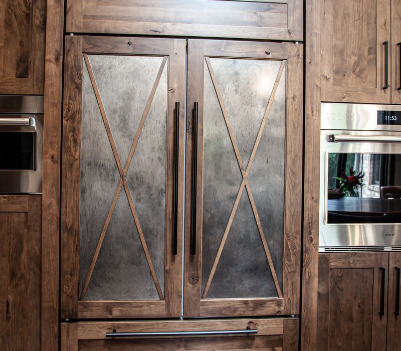 This house includes a brushed steel range hood, a live edge countertop, stone-seeded glass pendant lamps, skylights, and a barn door pantry. 