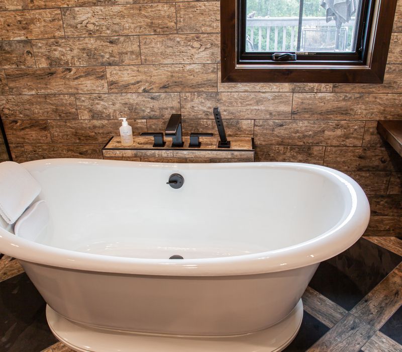 This house includes a brushed steel range hood, a live edge countertop, stone-seeded glass pendant lamps, skylights, and a barn door pantry. 