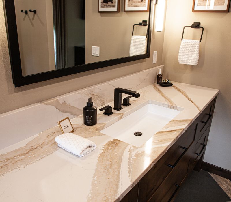 This house includes a brushed steel range hood, a live edge countertop, stone-seeded glass pendant lamps, skylights, and a barn door pantry. 