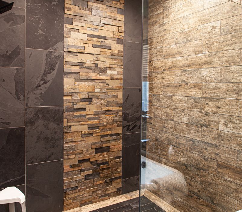 This house includes a brushed steel range hood, a live edge countertop, stone-seeded glass pendant lamps, skylights, and a barn door pantry. 