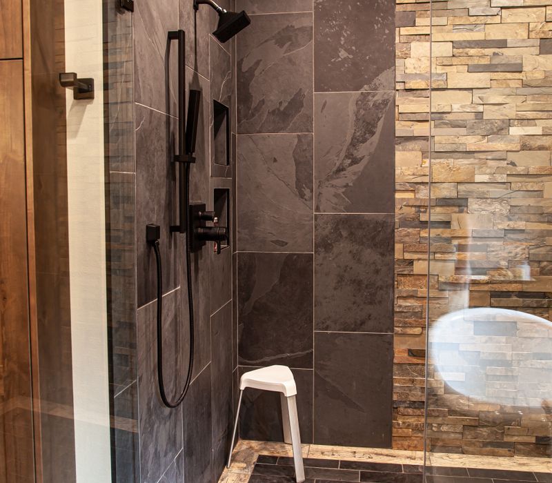 This house includes a brushed steel range hood, a live edge countertop, stone-seeded glass pendant lamps, skylights, and a barn door pantry. 