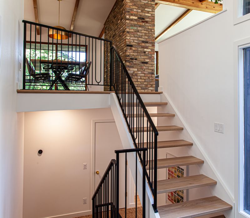 This remodeled split-level home features retro touches in an open contemporary space, and includes a craft room, central brick fireplace, exposed wood ceiling beams, and an open riser staircase. 