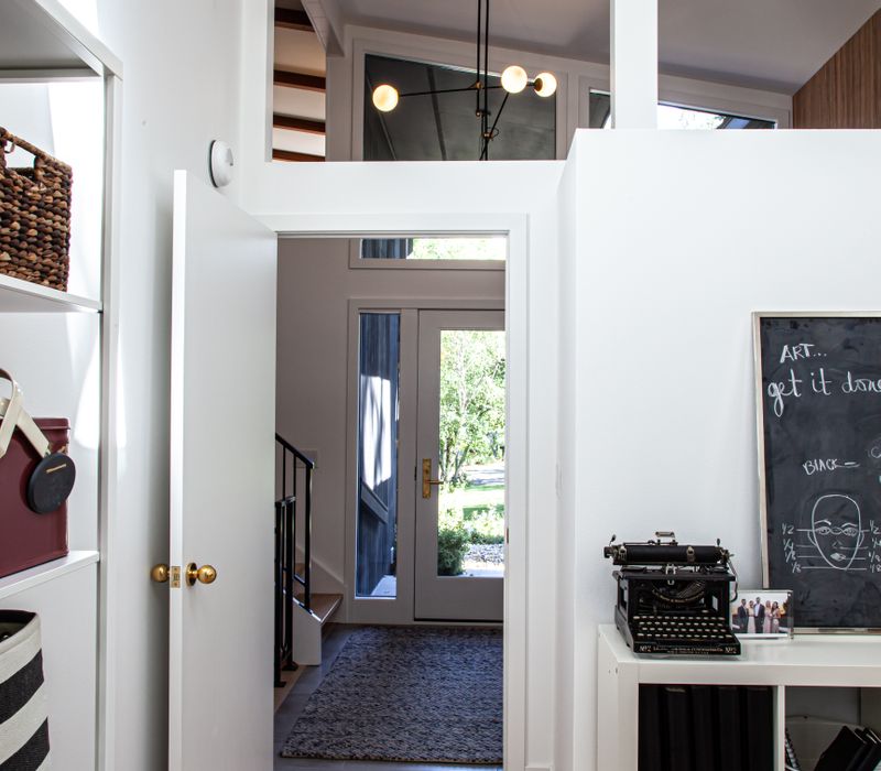 This remodeled split-level home features retro touches in an open contemporary space, and includes a craft room, central brick fireplace, exposed wood ceiling beams, and an open riser staircase. 