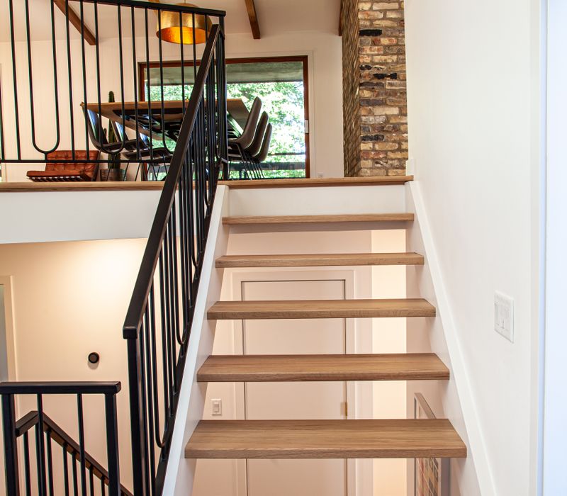 This remodeled split-level home features retro touches in an open contemporary space, and includes a craft room, central brick fireplace, exposed wood ceiling beams, and an open riser staircase. 