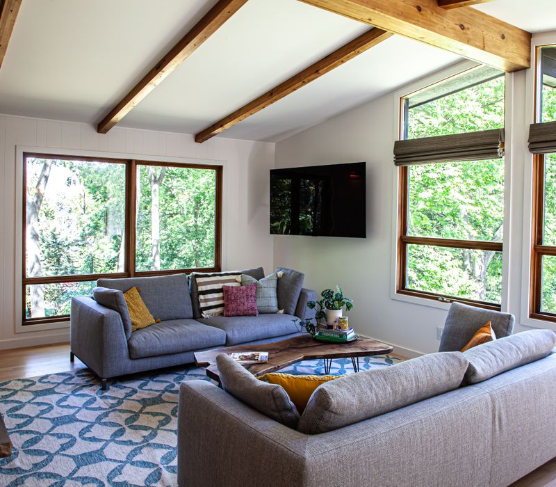 This remodeled split-level home features retro touches in an open contemporary space, and includes a craft room, central brick fireplace, exposed wood ceiling beams, and an open riser staircase. 