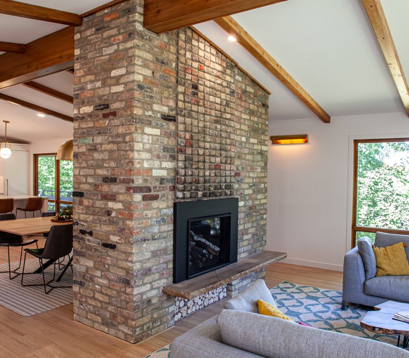 This remodeled split-level home features retro touches in an open contemporary space, and includes a craft room, central brick fireplace, exposed wood ceiling beams, and an open riser staircase. 