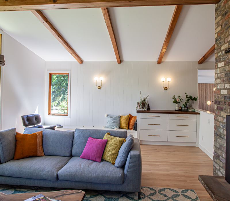 This remodeled split-level home features retro touches in an open contemporary space, and includes a craft room, central brick fireplace, exposed wood ceiling beams, and an open riser staircase. 