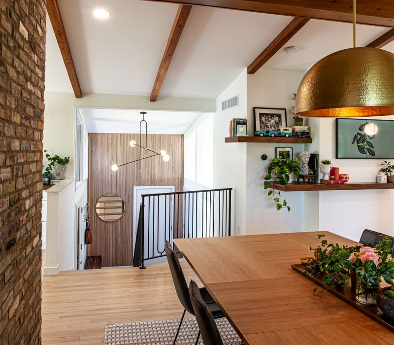 This remodeled split-level home features retro touches in an open contemporary space, and includes a craft room, central brick fireplace, exposed wood ceiling beams, and an open riser staircase. 