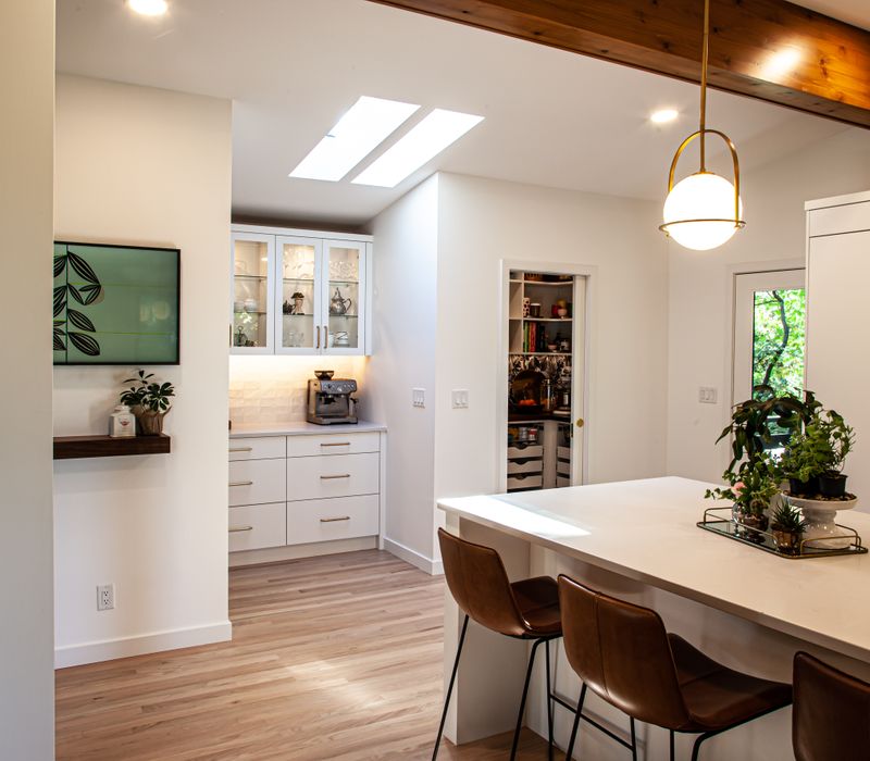 This remodeled split-level home features retro touches in an open contemporary space, and includes a craft room, central brick fireplace, exposed wood ceiling beams, and an open riser staircase. 