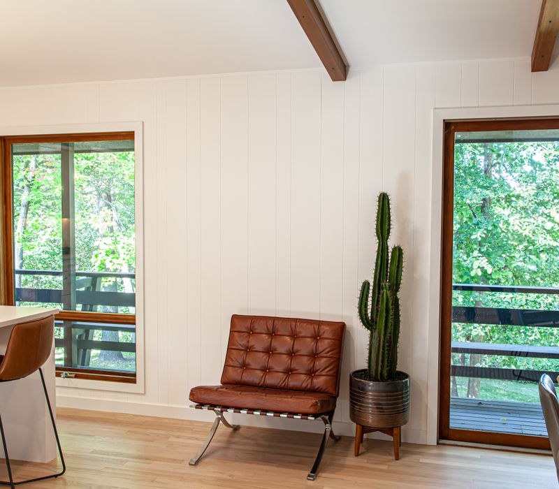 This remodeled split-level home features retro touches in an open contemporary space, and includes a craft room, central brick fireplace, exposed wood ceiling beams, and an open riser staircase. 