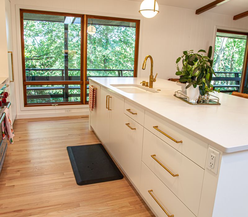 This remodeled split-level home features retro touches in an open contemporary space, and includes a craft room, central brick fireplace, exposed wood ceiling beams, and an open riser staircase. 
