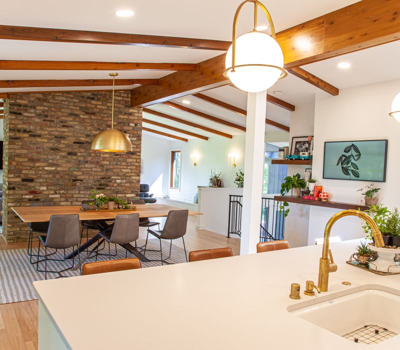 This remodeled split-level home features retro touches in an open contemporary space, and includes a craft room, central brick fireplace, exposed wood ceiling beams, and an open riser staircase. 