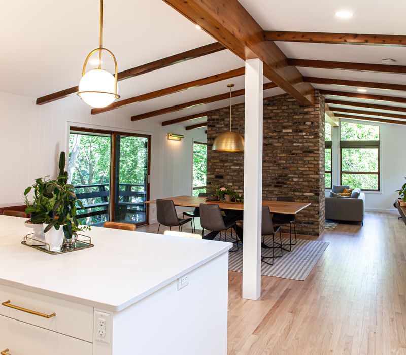 This remodeled split-level home features retro touches in an open contemporary space, and includes a craft room, central brick fireplace, exposed wood ceiling beams, and an open riser staircase. 