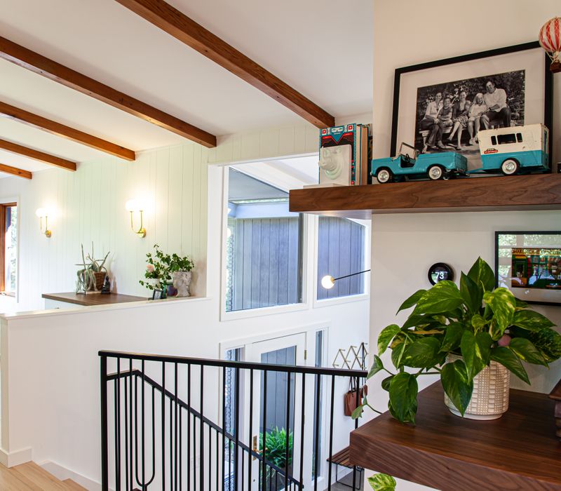 This remodeled split-level home features retro touches in an open contemporary space, and includes a craft room, central brick fireplace, exposed wood ceiling beams, and an open riser staircase. 