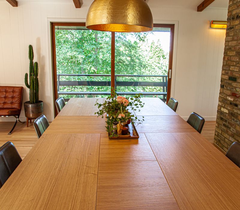 This remodeled split-level home features retro touches in an open contemporary space, and includes a craft room, central brick fireplace, exposed wood ceiling beams, and an open riser staircase. 