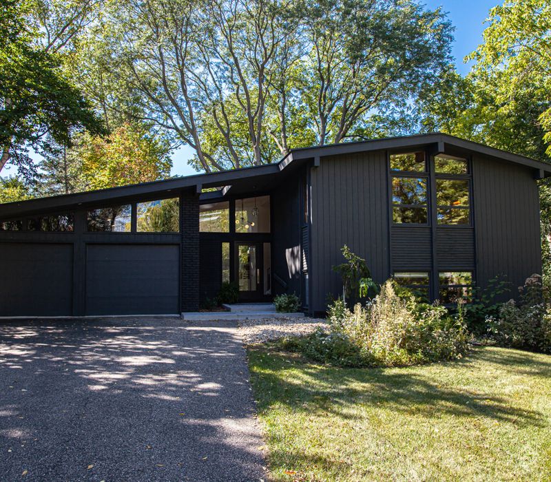 This remodeled split-level home features retro touches in an open contemporary space, and includes a craft room, central brick fireplace, exposed wood ceiling beams, and an open riser staircase. 
