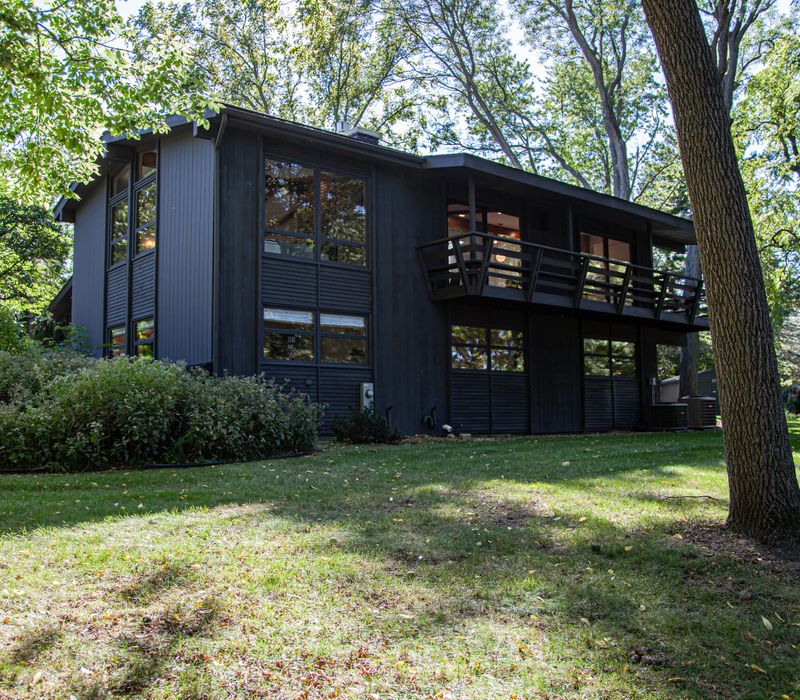 This remodeled split-level home features retro touches in an open contemporary space, and includes a craft room, central brick fireplace, exposed wood ceiling beams, and an open riser staircase. 