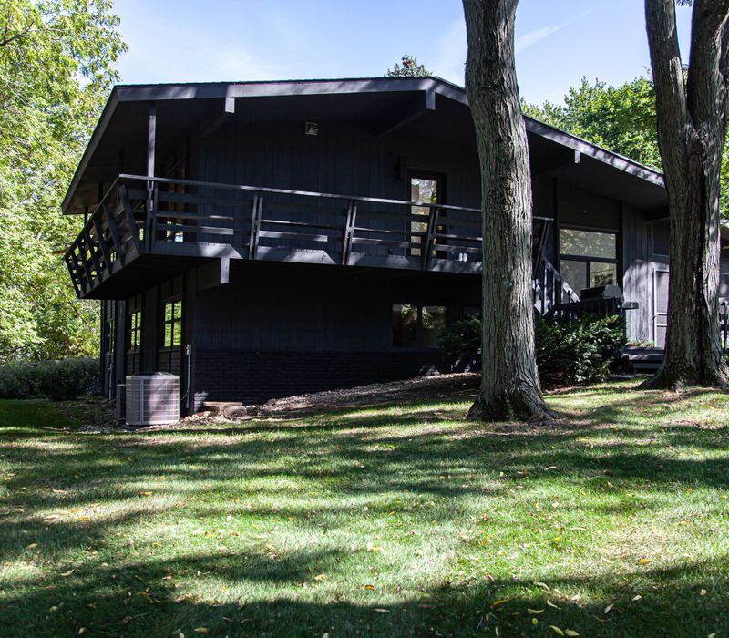 This remodeled split-level home features retro touches in an open contemporary space, and includes a craft room, central brick fireplace, exposed wood ceiling beams, and an open riser staircase. 