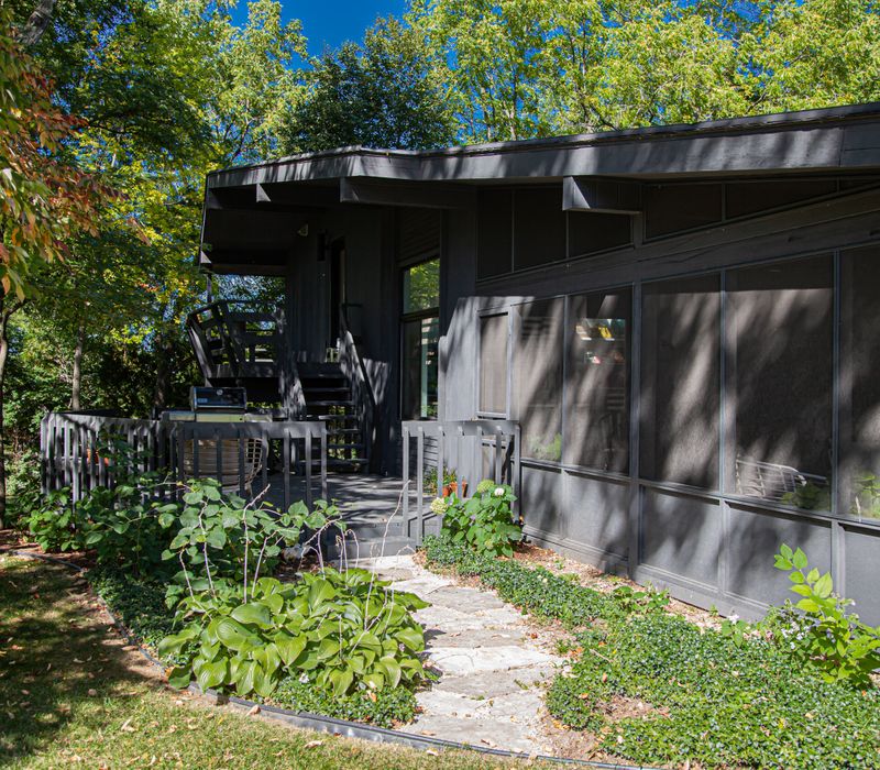 This remodeled split-level home features retro touches in an open contemporary space, and includes a craft room, central brick fireplace, exposed wood ceiling beams, and an open riser staircase. 