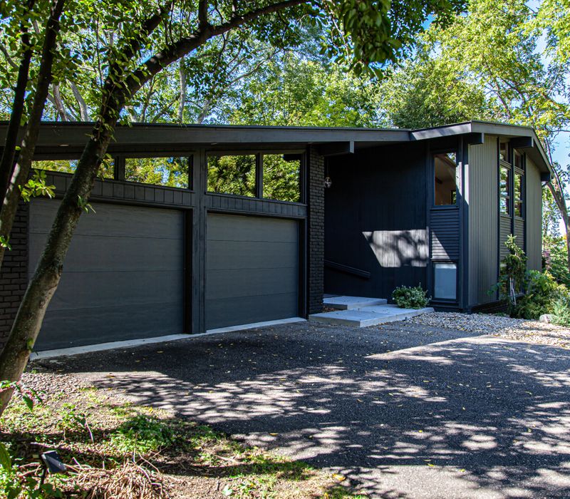This remodeled split-level home features retro touches in an open contemporary space, and includes a craft room, central brick fireplace, exposed wood ceiling beams, and an open riser staircase. 