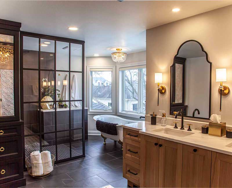 Elegance reigns supreme in this bathroom remodel that features an en suite, walk-in closet, walk-in shower, custom double vanity, private water closet, framed-glass barn doors, and a dazzling starburst chandelier.