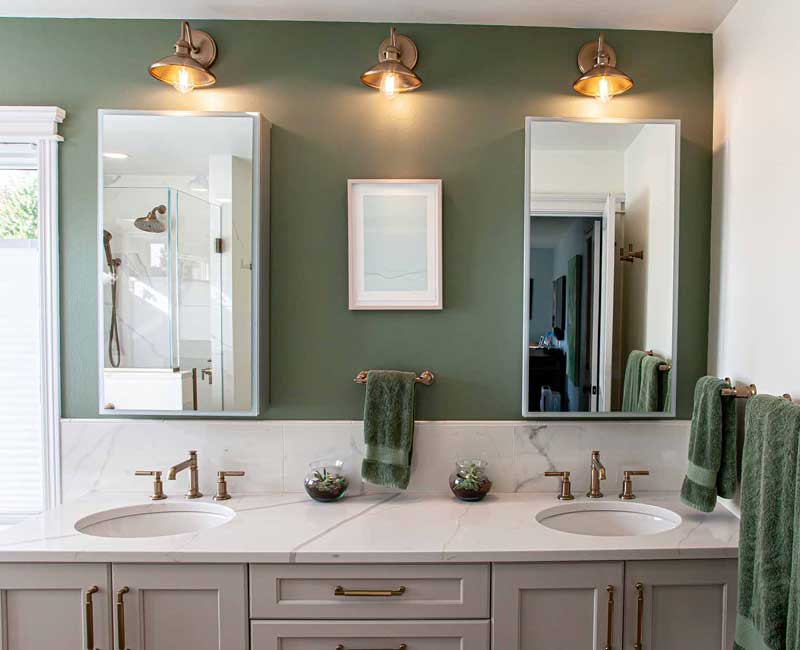 The pairing of cool stone and earthy tones in this bathroom remodel evokes the hush of a private spa. The bathroom features a Japanese soaking tub, custom double vanity, shower with dual showerheads, and lots of natural light.