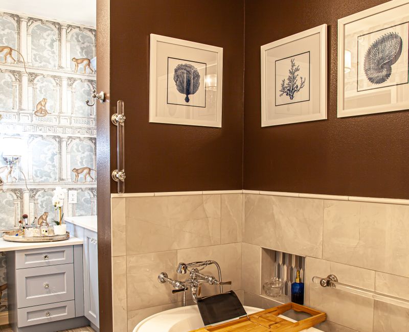 Wallpaper featuring monkeys posing on Venetian architecture, light blue cabinets, and elongated hexagon mosaic tiles add interest to this elegant bathroom with laundry machines and an attached walk-in closet.