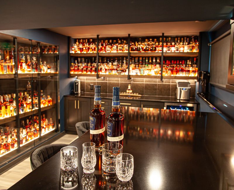 These dramatic lighted cabinets showcase an extensive liquor collection, while the bar provides a convenient spot to enjoy it, and the basement rec room a place to unwind.