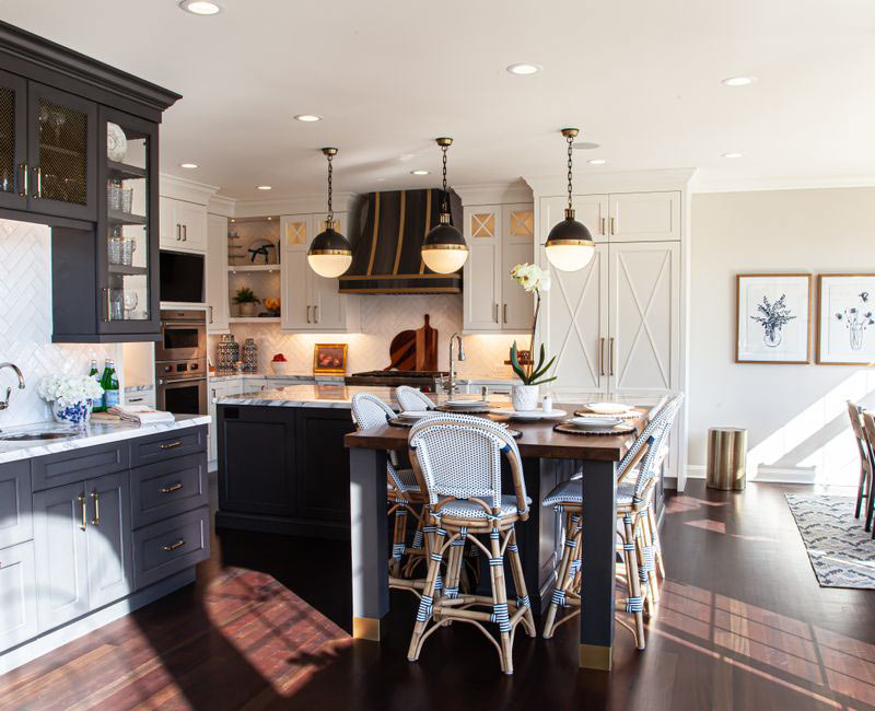This light-filled, European inspired kitchen includes a bay windowed breakfast nook and opens onto an expansive deck. The striking black cabinetry coordinates with the black and brass pendant lamps and range hood.