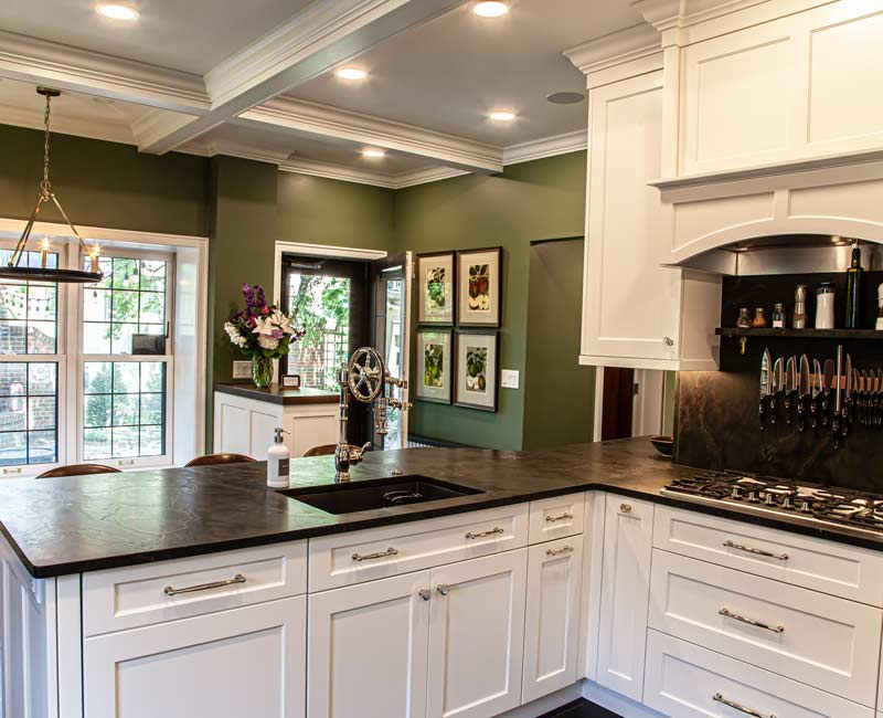 A chrome pull-down wheel faucet is the centerpiece of this traditional kitchen with natural slate countertops, art nouveau floral wallpaper, and green walls.