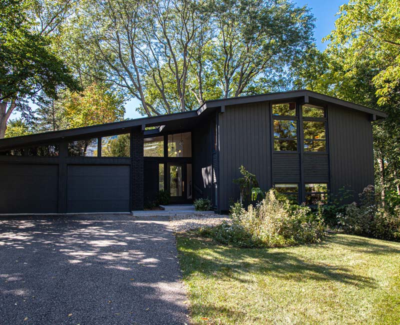 This remodeled split-level home features retro touches in an open contemporary space, and includes a craft room, central brick fireplace, exposed wood ceiling beams, and an open riser staircase. 